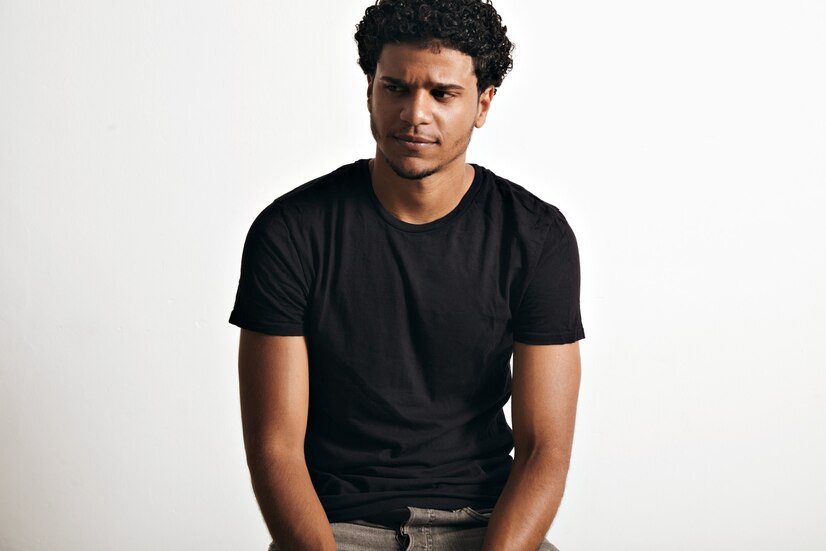 ironic-thoughtful-handsome-young-man-with-afro-wearing-black-sleeveless-cotton-t-shirt-white-wall_346278-1011